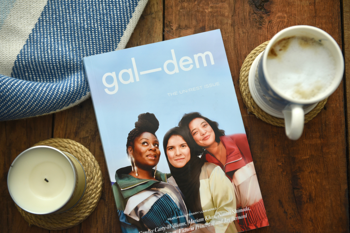 Gal-dem UN/REST magazine issue on wooden table with candle, coffee cup and blanket